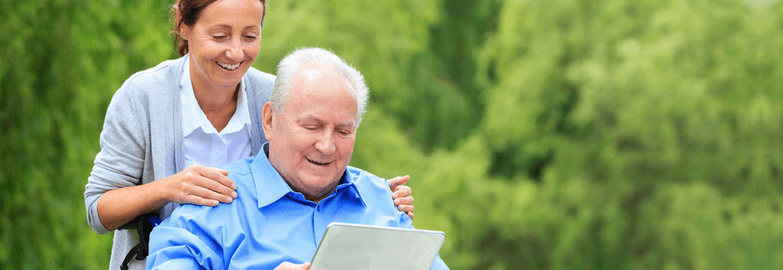 provider of senior care in Edmonton laughing with elderly man in wheelchair outside